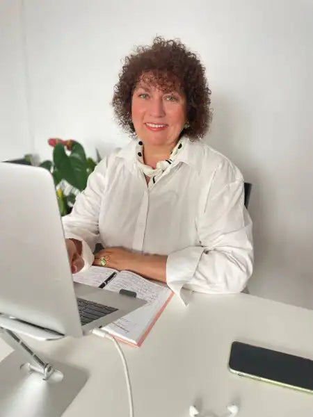 Woman with curly brown hair working on a laptop, coach Valentyna Melnyk guide Woman with curly brown hair working on a laptop, coach Valentyna Melnyk guide
