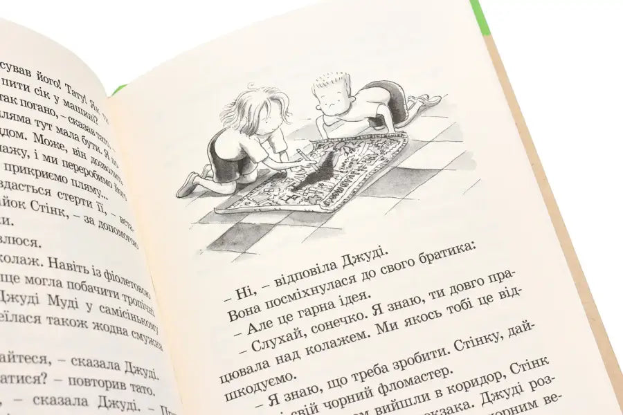 Open book with an illustration of two children drawing on a rug.