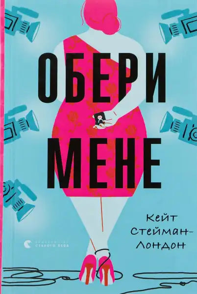 Book cover of One to Watch Ukrainian Edition by Kate Stayman-London with a woman in pink surrounded by cameras Book cover of One to Watch Ukrainian Edition by Kate Stayman-London with a woman in pink surrounded by cameras