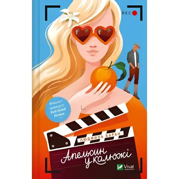 Book cover with a blonde woman holding an orange from the English books Orange in a Puddle Book cover with a blonde woman holding an orange from the English books Orange in a Puddle