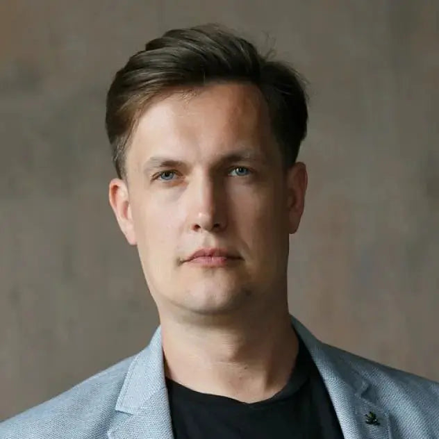 Max Kidruk man with heterochromia wearing a blazer, showcasing English books collection