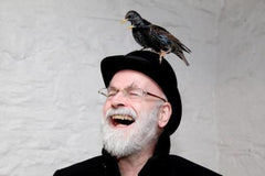 Laughing man with bird from terry pratchett’s books in an English books collection