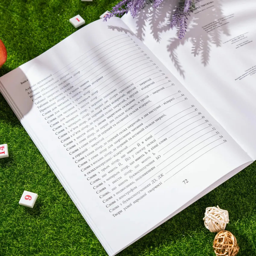 Open book page with text on reading exercises, surrounded by decorative elements on green grass.