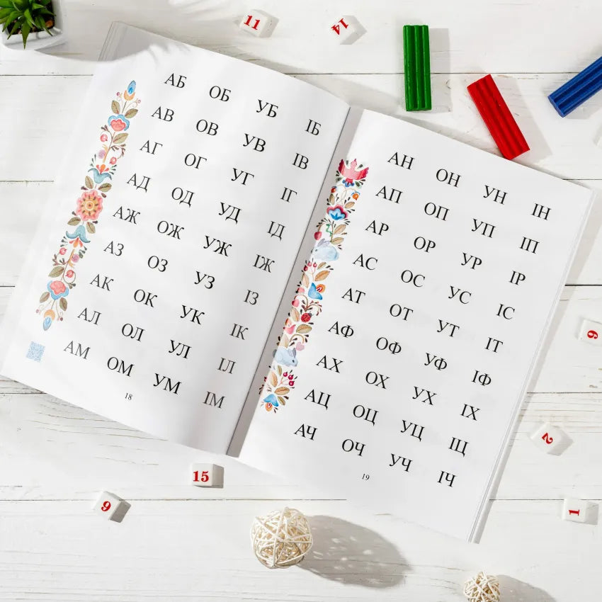 Open book pages displaying Ukrainian alphabet with floral decorations, ideal for children's reading lessons.