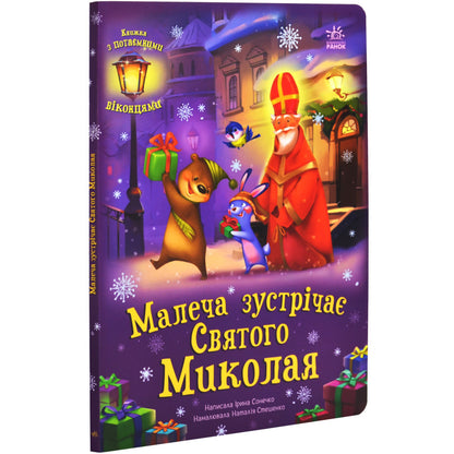 Книга 'Малеча зустрічає Святого Миколая' з образами Святого Миколая та лісових звірят у зимовій атмосфері.