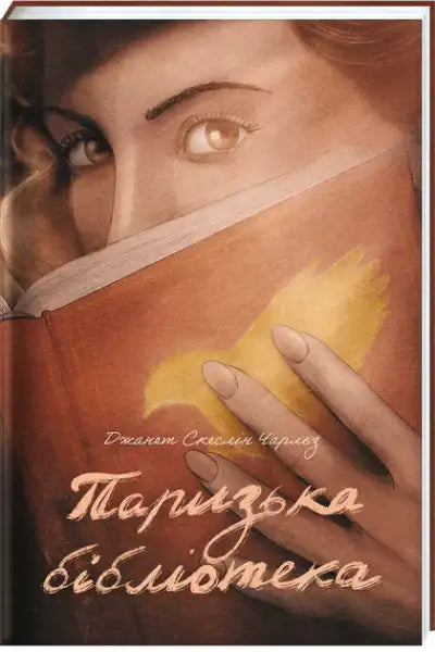 Book cover of The Paris Library by Janet Skeslien Charles with woman’s eyes and golden bird