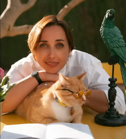 Zelena Papuga Event: Woman with short brown hair and wristwatch resting with ginger cat in a cozy setting